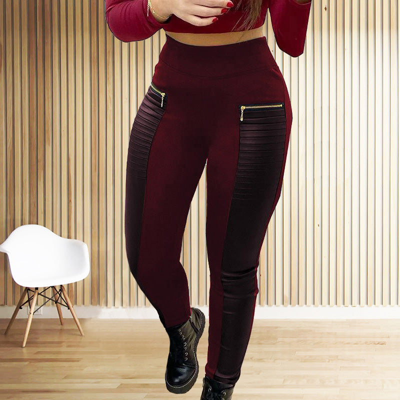 Person wearing burgundy leggings with zippers in a room with wooden flooring and a white chair.
