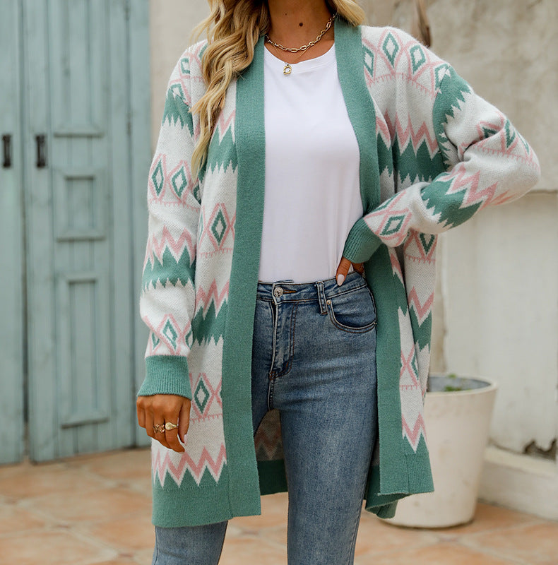 Person wearing a green and white patterned cardigan over a white shirt and jeans, standing outdoors.