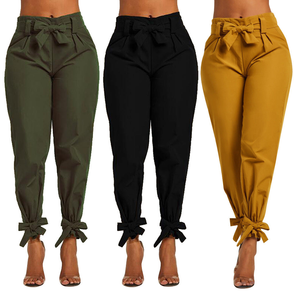 Three pairs of pants in green, black, and mustard yellow with tied cuffs on a white background.