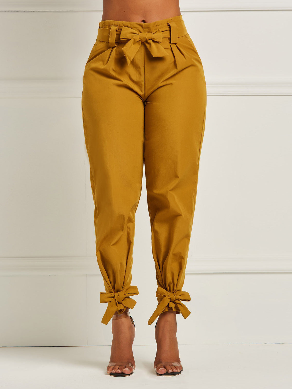 Mustard yellow pants with tied cuffs and waistband on a white background